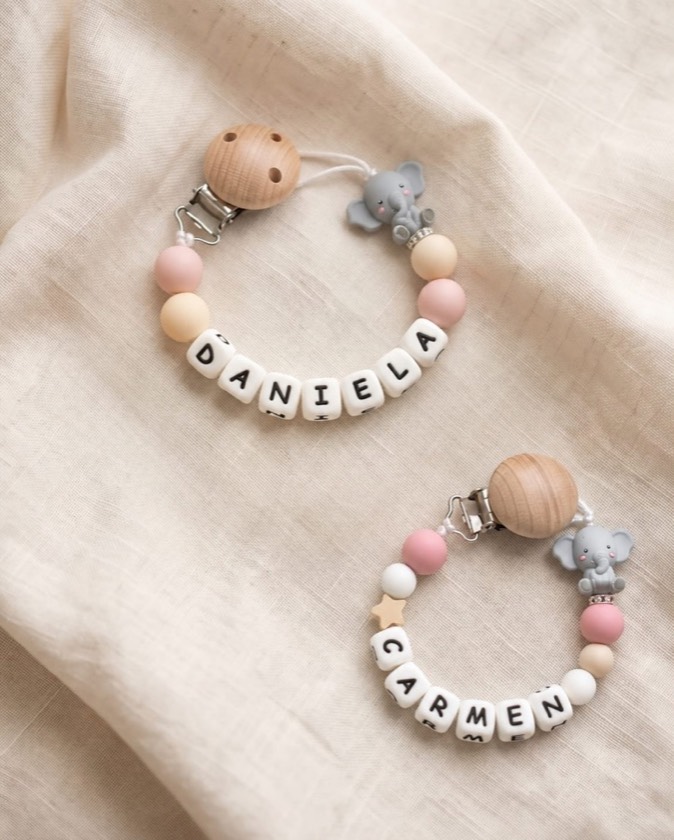 Dos chupeteros rosas con los nombres DANIELA y CARMEN y charms de elefante